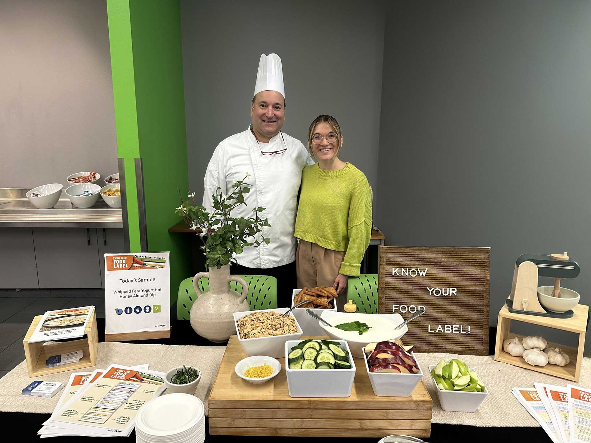 Chef and a dietitian smiling at display table